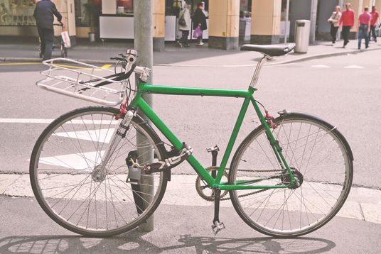Green bicycle locked to a lamp post 